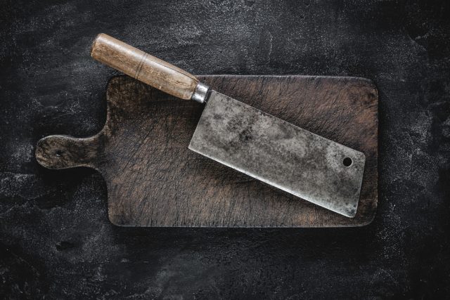 rustic cutting board and meat cleaver on dark background