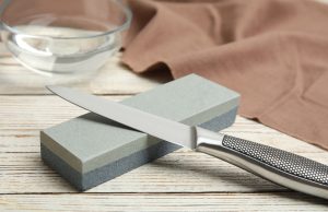 What is the Term For a Knife-Sharpening Stone? sharpening stone and knife on white wooden table